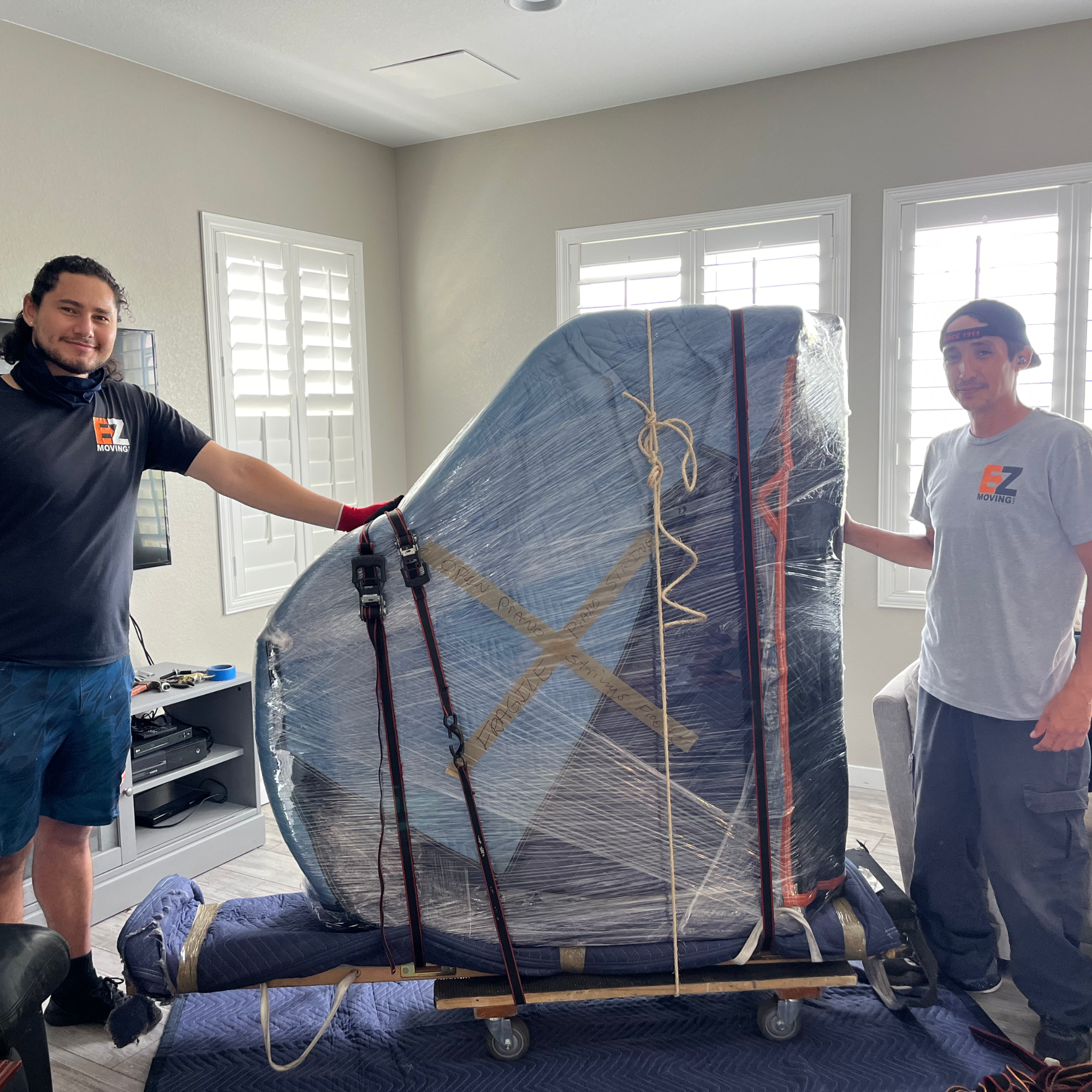 EZ Moving team wrapping grand piano in living room