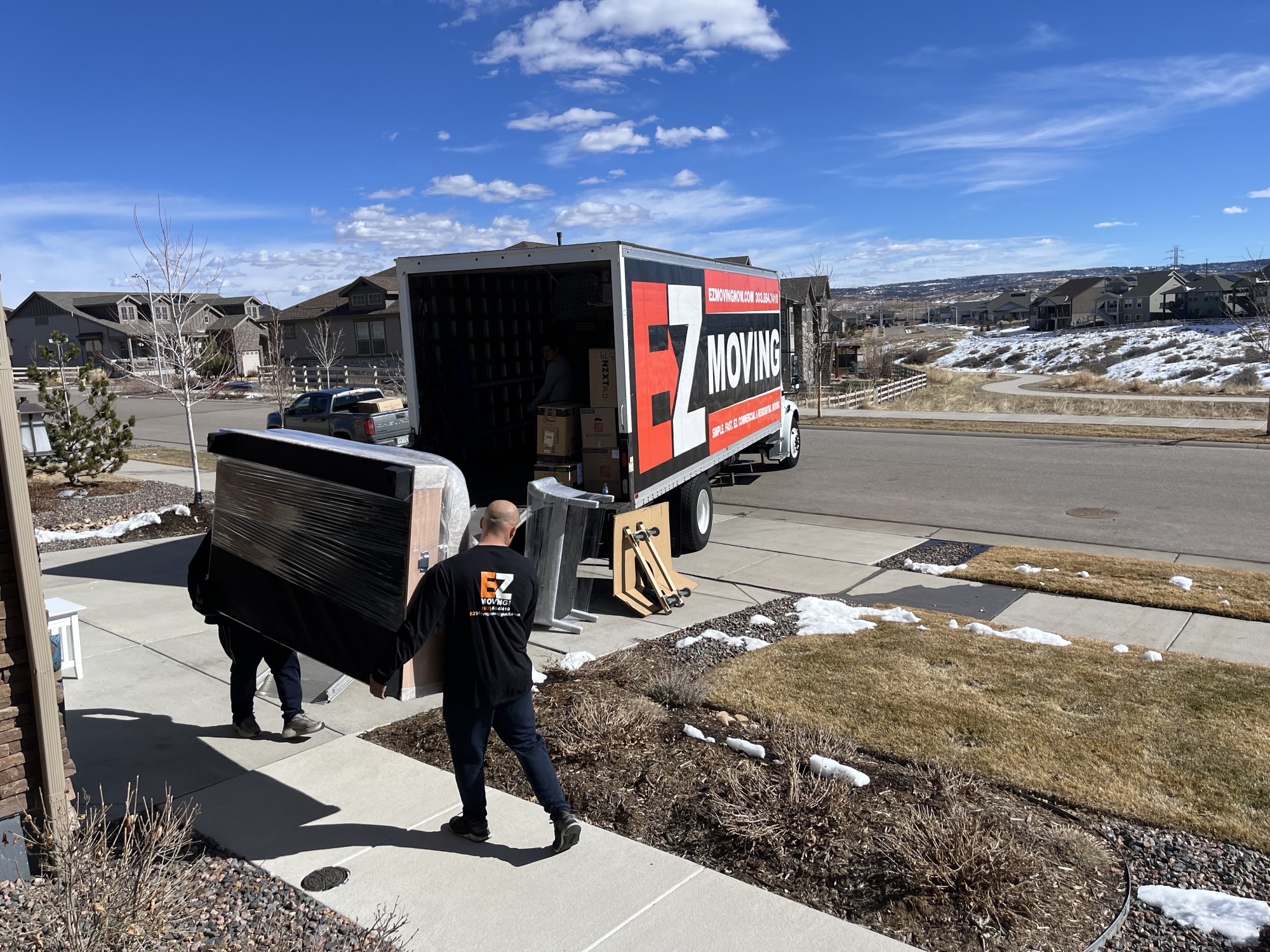 EZ Moving employees loading a piece of furniture into their truck