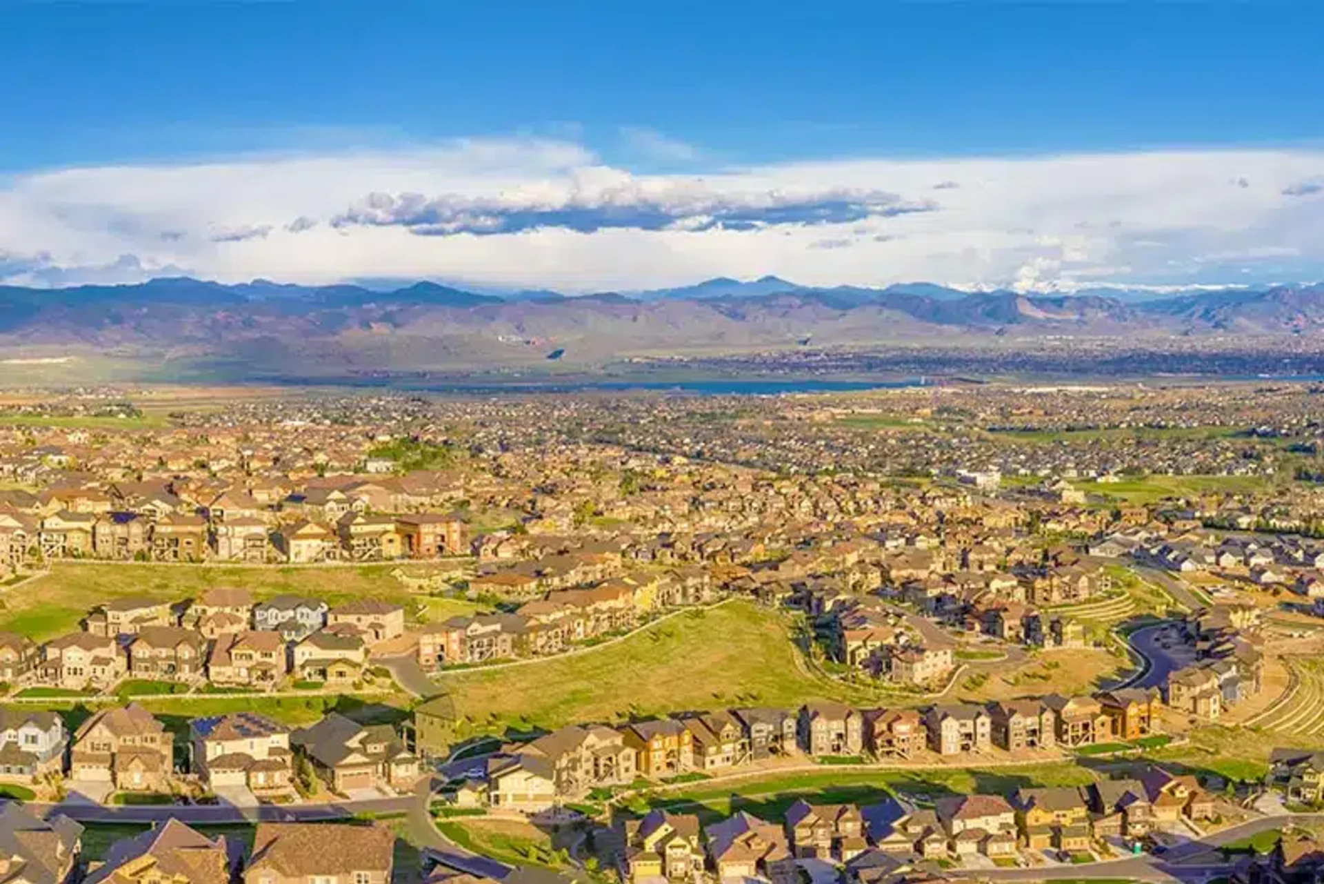 Aerial image of Suburban Highlands Ranch Colorado with homes, mountains, and clouds