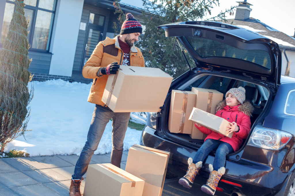 family moving in snowy weather loading boxes into the car 